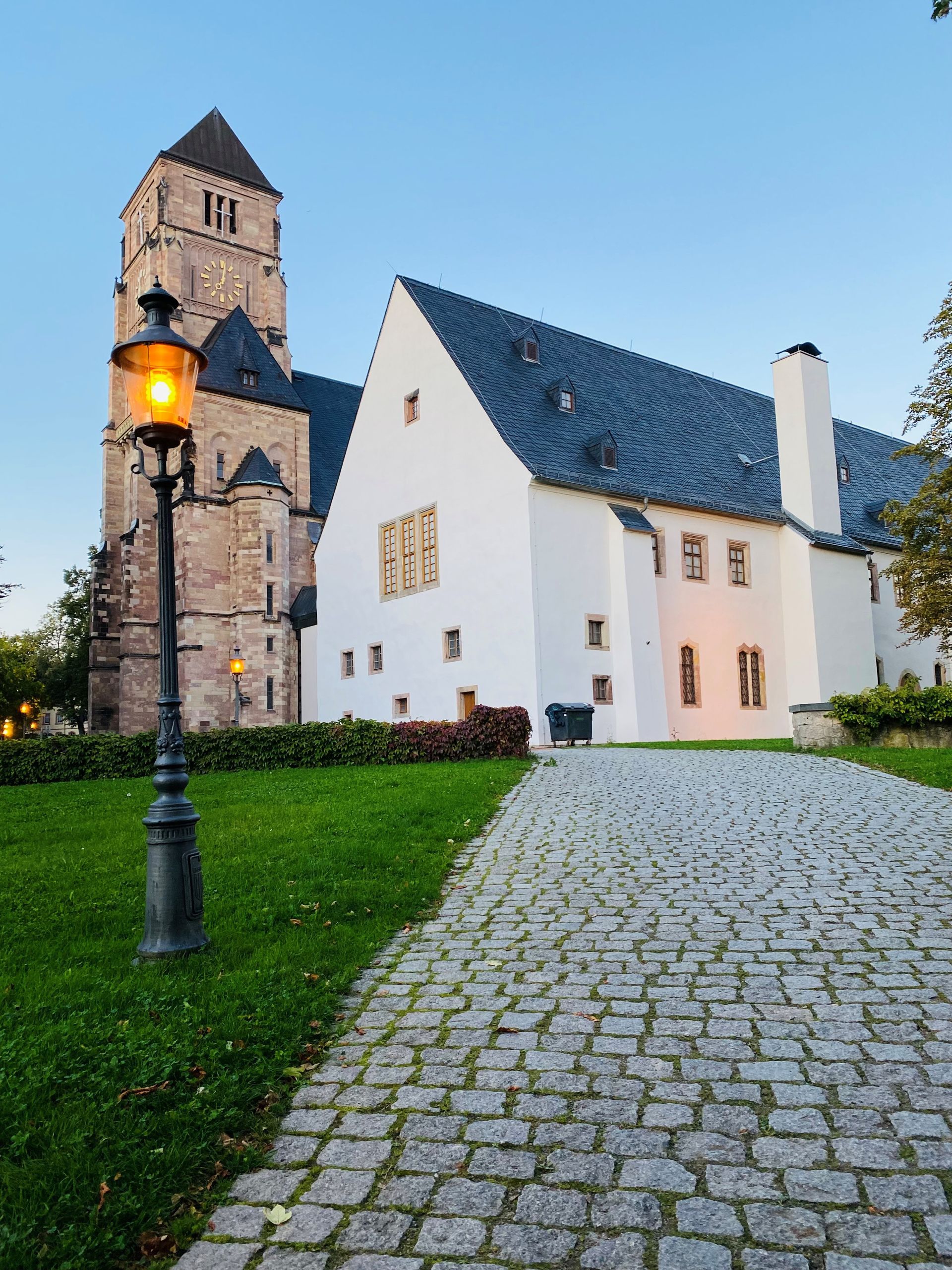 Menschen betrachten eine Reihe schwarzer und roter Dampflokomotiven in einer großen Lokhalle.