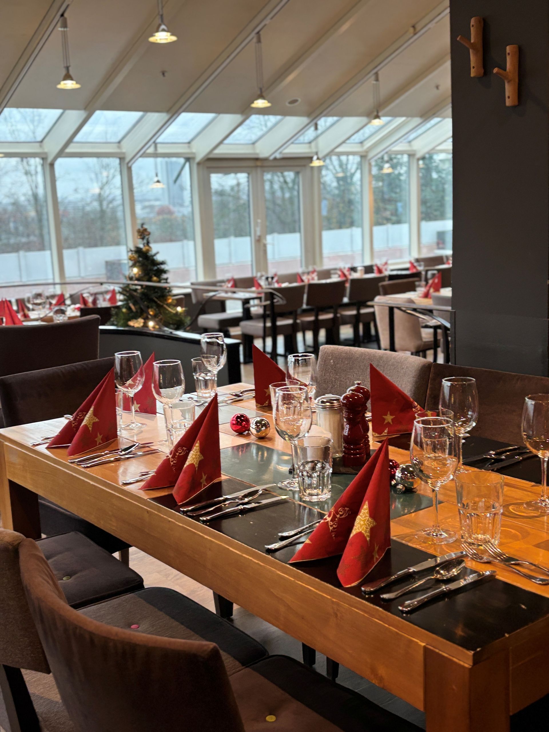 Restaurant-Speisesaal mit Tischen, roten Servietten, Gläsern und Weihnachtsbaum.