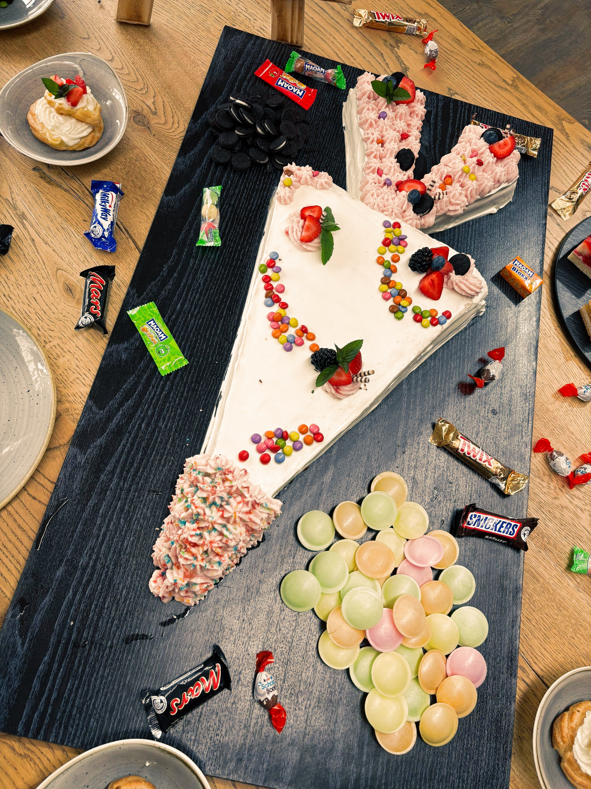 Ein mit Süßigkeiten und Früchten dekoriertes Kuchenstück auf einer Platte.