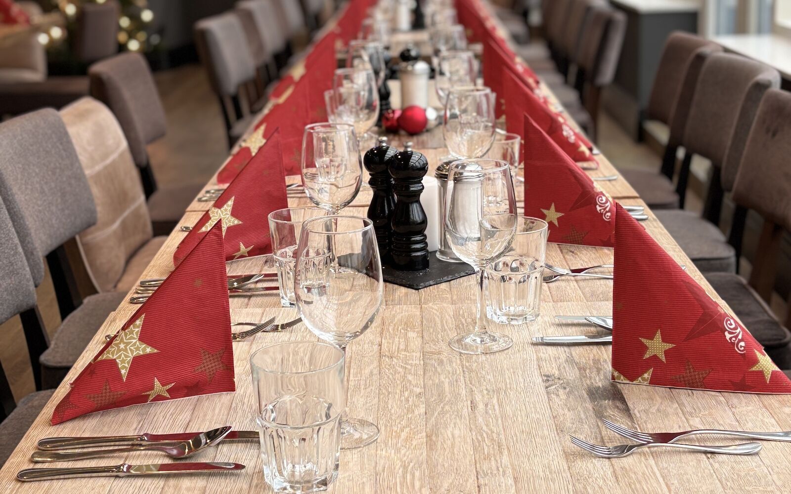 Ein langer Esstisch ist für ein Festessen gedeckt, mit roten Servietten, Gläsern und Geschirr mit Sternenmuster.