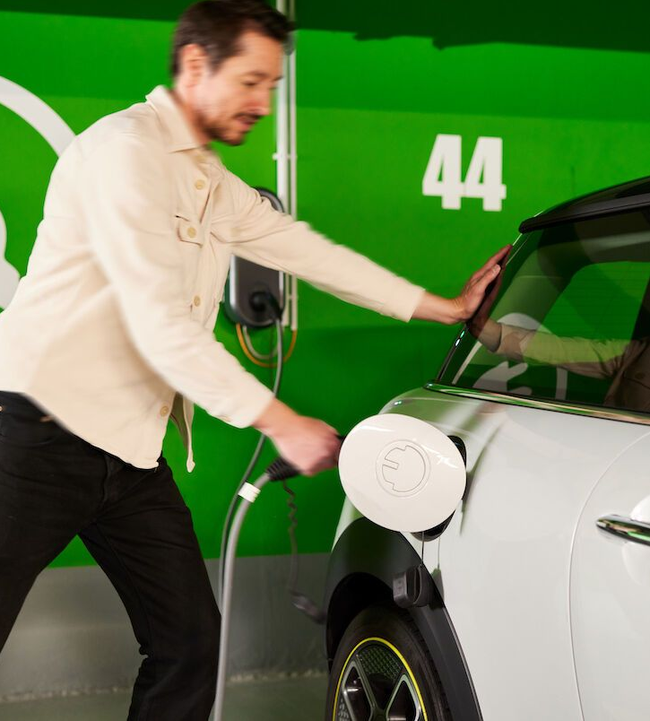 Ein Mann läd sein E-Auto an einer Ladestation.