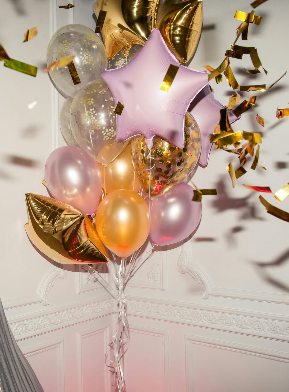 Luftballons in Gold-, Rosa- und Lavendeltönen, mit Konfetti.