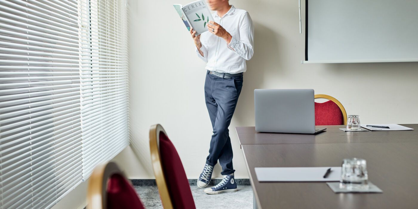 Eine Gruppe von Menschen steht vor einem Gebäude auf einer Rasenfläche. Die meisten lächeln und tragen dunkle Kleidung.