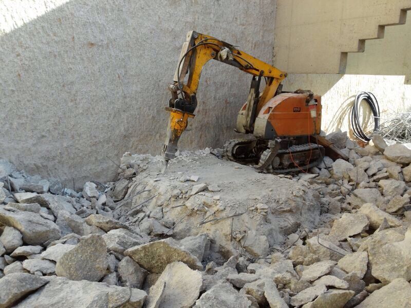 Una excavadora amarilla está rompiendo rocas en una pila