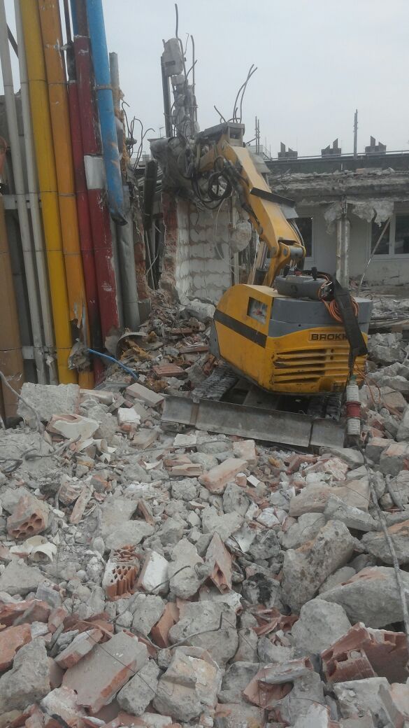 Una excavadora amarilla está demoliendo un edificio.
