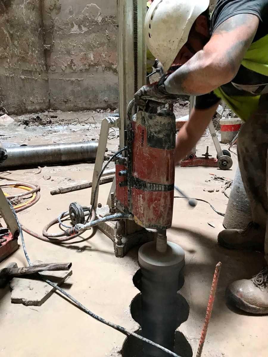 Un hombre está usando una máquina para hacer agujeros en el suelo.