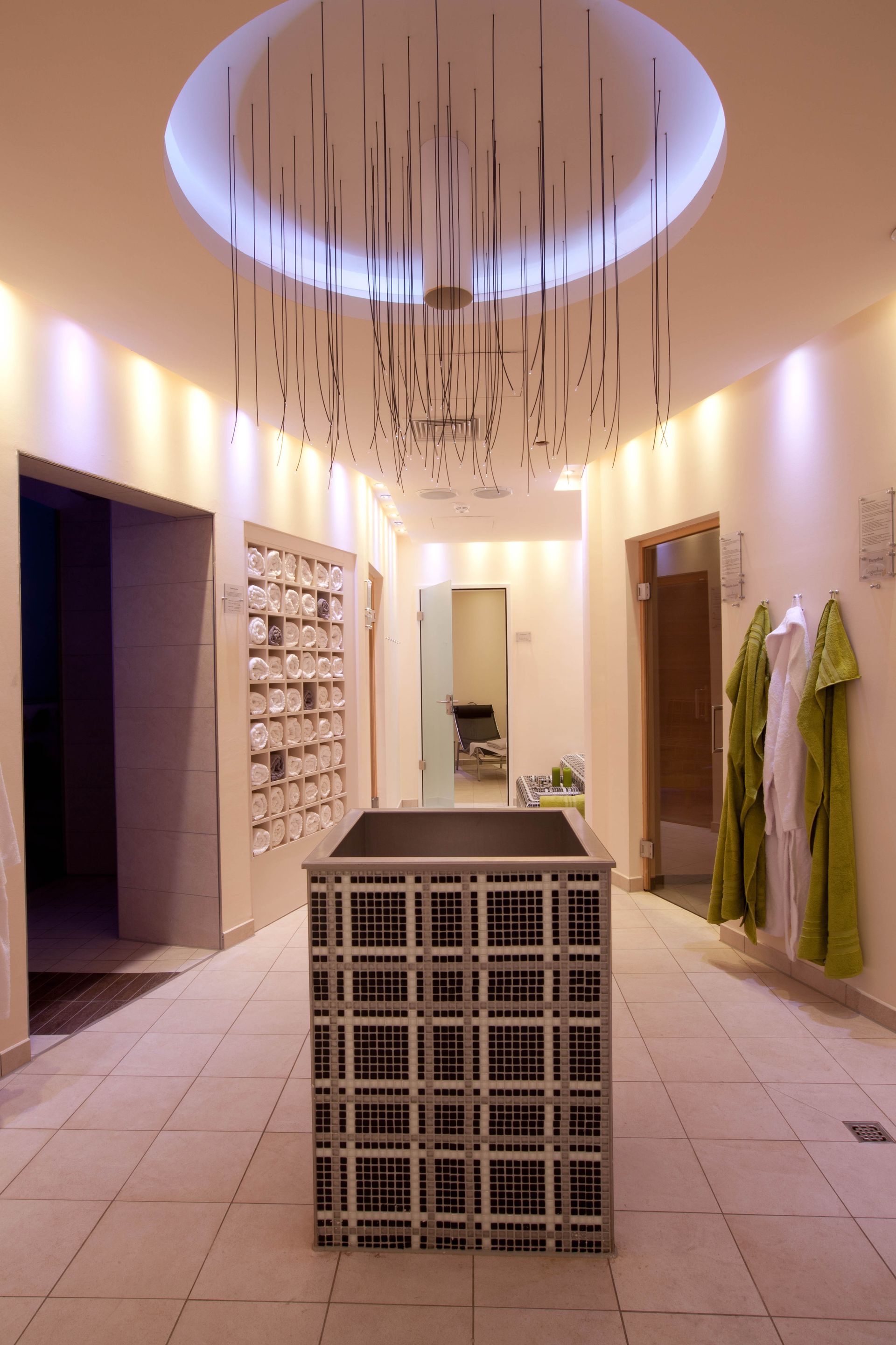 Spa-Flur mit offenem Gittertisch, Hängelampen und Türen.