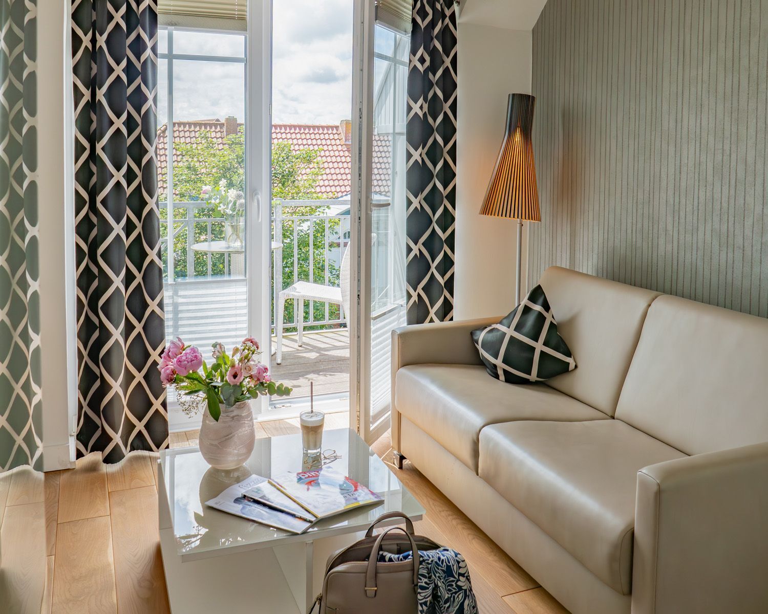 Sandstrand mit hohem Gras im Vordergrund, Meer und untergehende Sonne im Hintergrund.