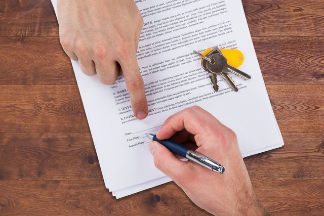 Eine Person schreibt mit einem Stift auf ein Blatt Papier.