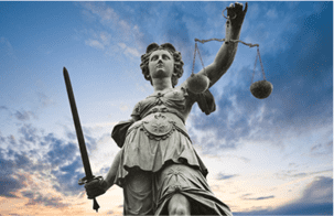 Estatua de la Dama de la Justicia sosteniendo una balanza y una espada contra un cielo azul nublado.