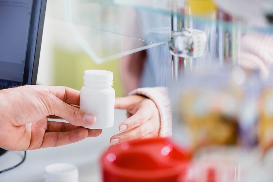 Entregar un frasco de pastillas blanco en el mostrador de una farmacia.