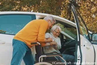 Ältere Frau im Rollstuhl wird beim Aussteigen geholfen