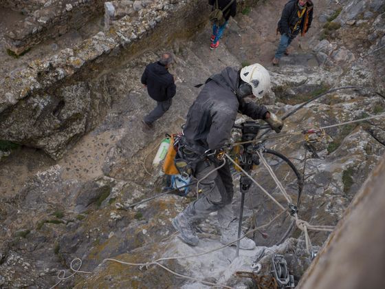 Ouvrier travaillant sur corde en milieu escarpé à l'aide d'un marteau-piqueur