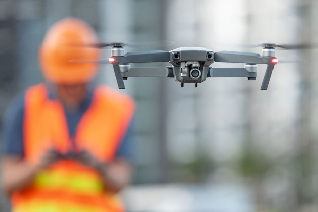 Drone au décollage avec ouvrier en tenue de sécurité en arrière-plan