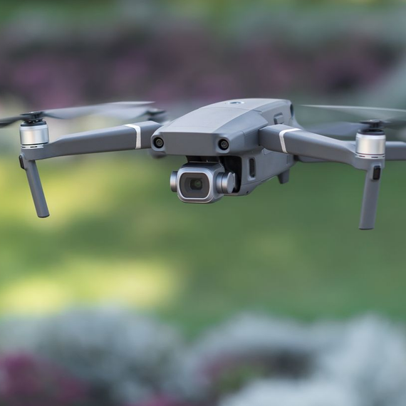 Drone gris en vol stationnaire à l'extérieur avec un arrière-plan vert flou