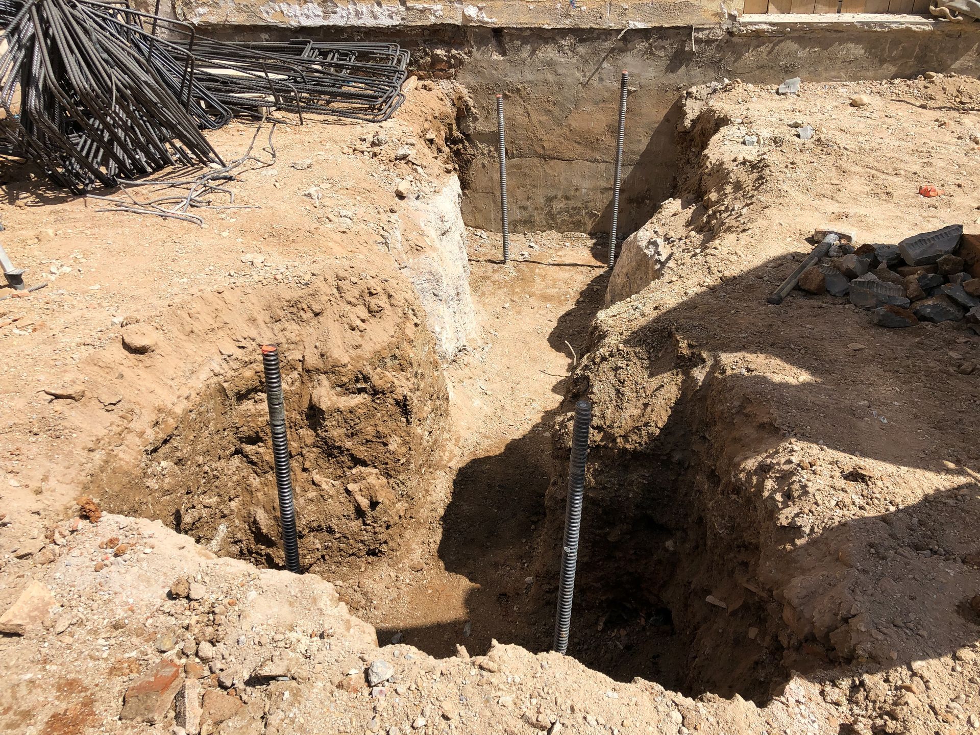 Grande fosse d'excavation avec parois de tranchée et canalisations apparentes sur un chantier de construction
