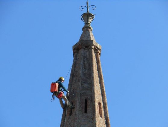 Ouvrier réalisant des travaux sur corde au niveau du clocher d'un monument ancien