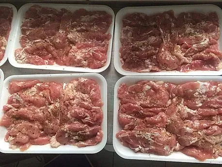 Un montón de bandejas de carne están sobre una mesa.