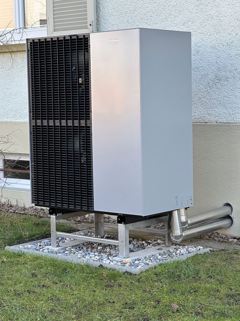 Eine große graue Kiste steht im Gras neben einem Gebäude.