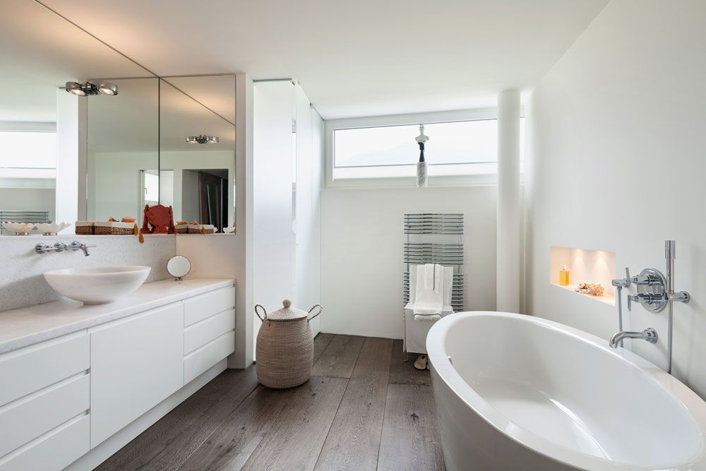 Helles, modernes Badezimmer mit freistehender Badewanne, Waschtisch mit Doppelwaschbecken und großem Wandspiegel