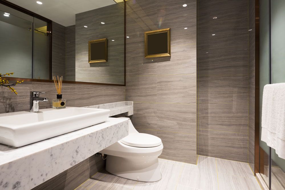 Modernes Badezimmer mit schwebendem Waschtisch, großem Spiegel, Kunstwerk mit goldenem Rahmen und wandhängendem WC