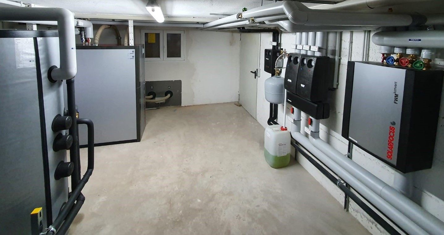 Ein Raum mit vielen Rohren und ein paar Kästen an der Wand.