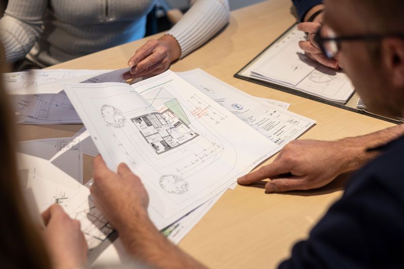 Eine Frau sitzt mit einem Laptop und einem Taschenrechner an einem Tisch.