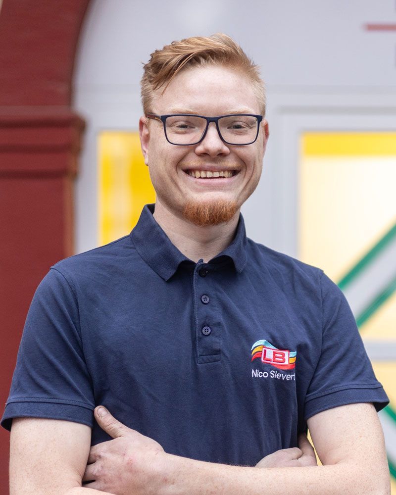 Ein Mann mit Brille und Bart lächelt in die Kamera.