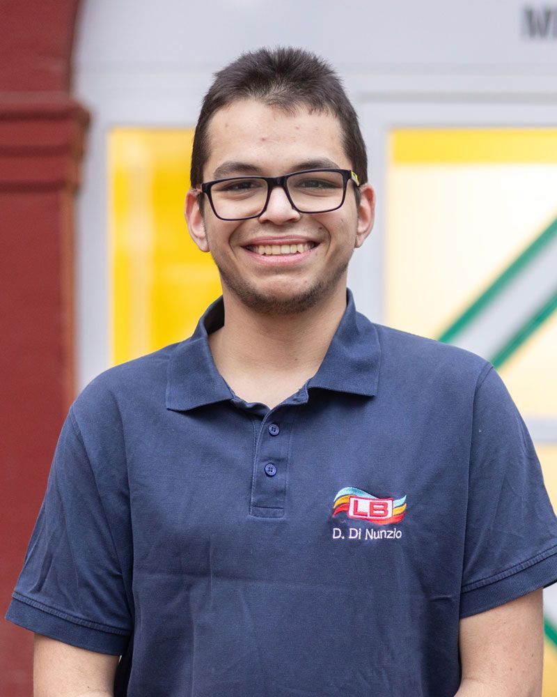 Ein junger Mann mit Brille und blauem Hemd lächelt