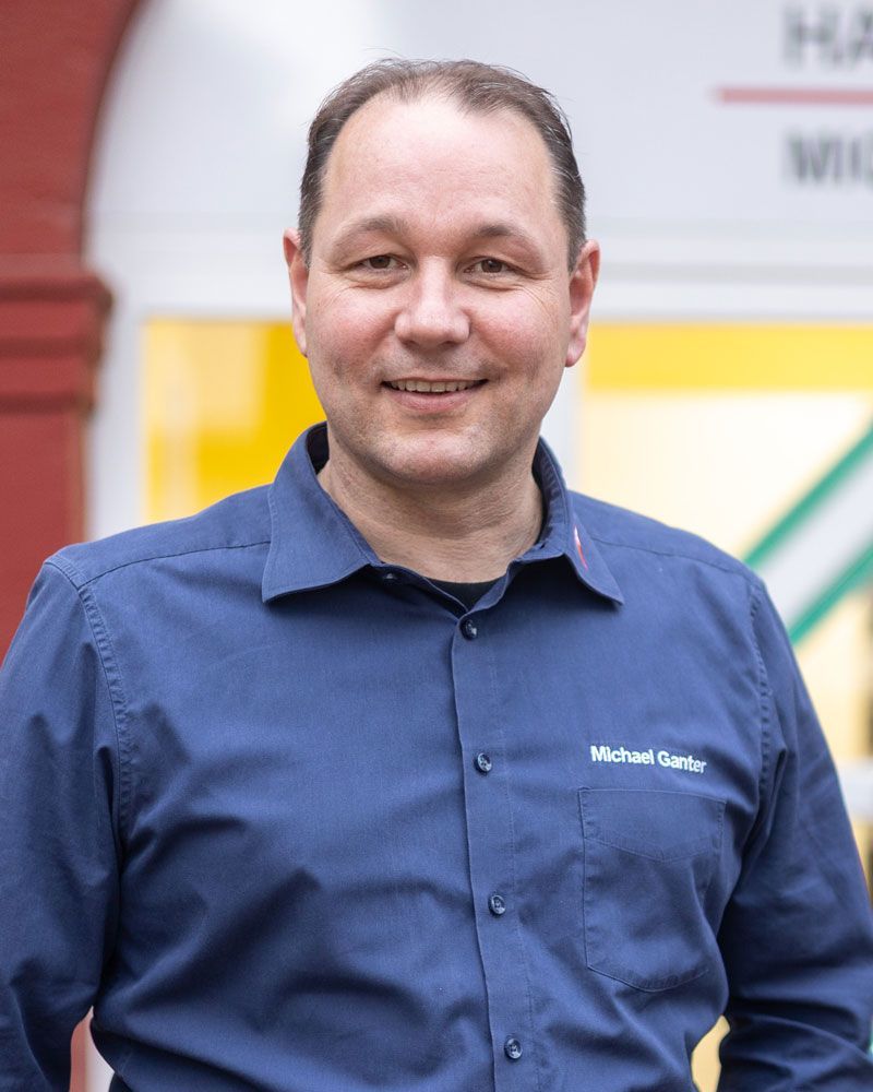 Ein Mann in einem blauen Poloshirt lächelt in die Kamera.