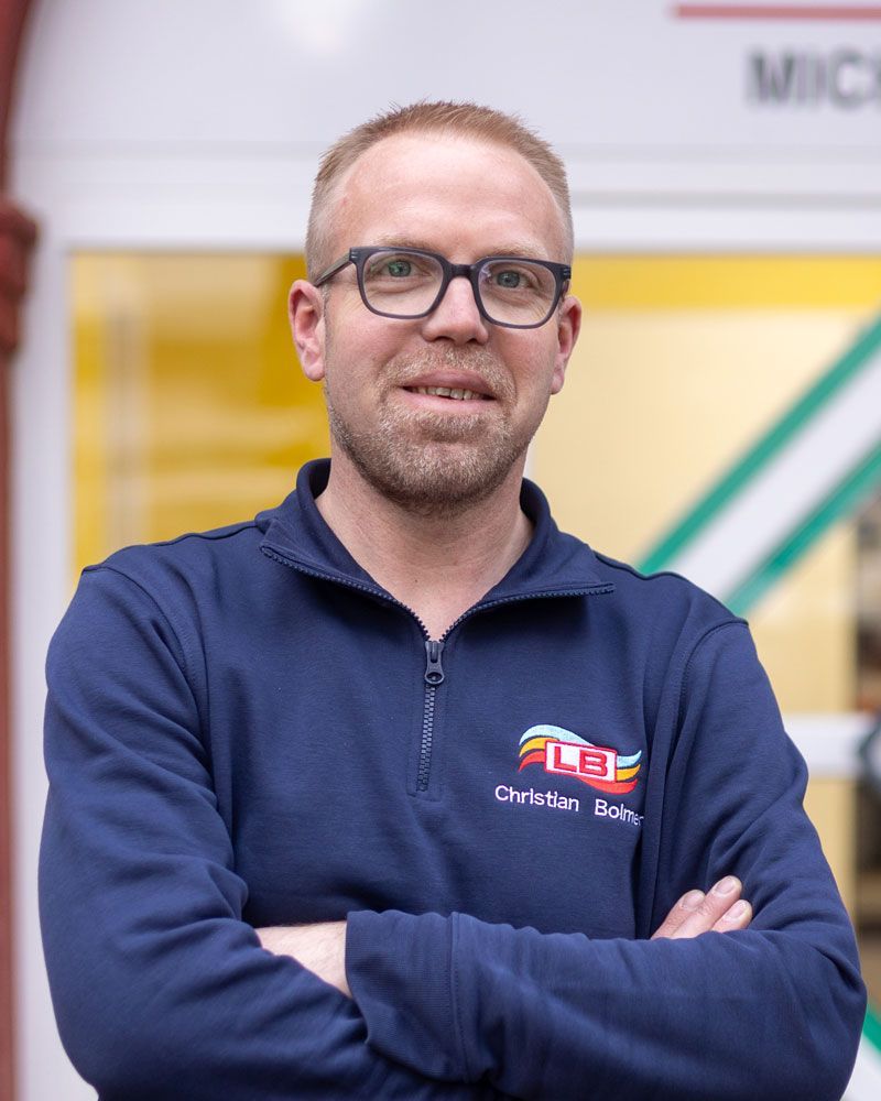 Ein Mann mit Brille und Bart lächelt in die Kamera.