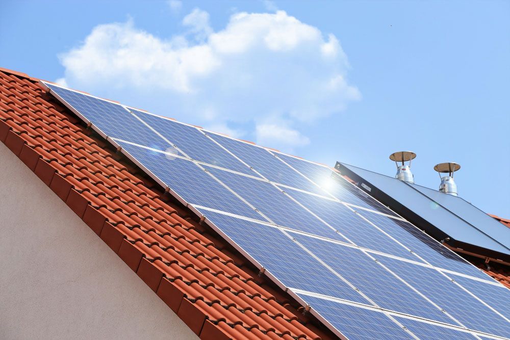 Solarmodule auf einem rot gedeckten Dach unter blauem Himmel mit Wolken
