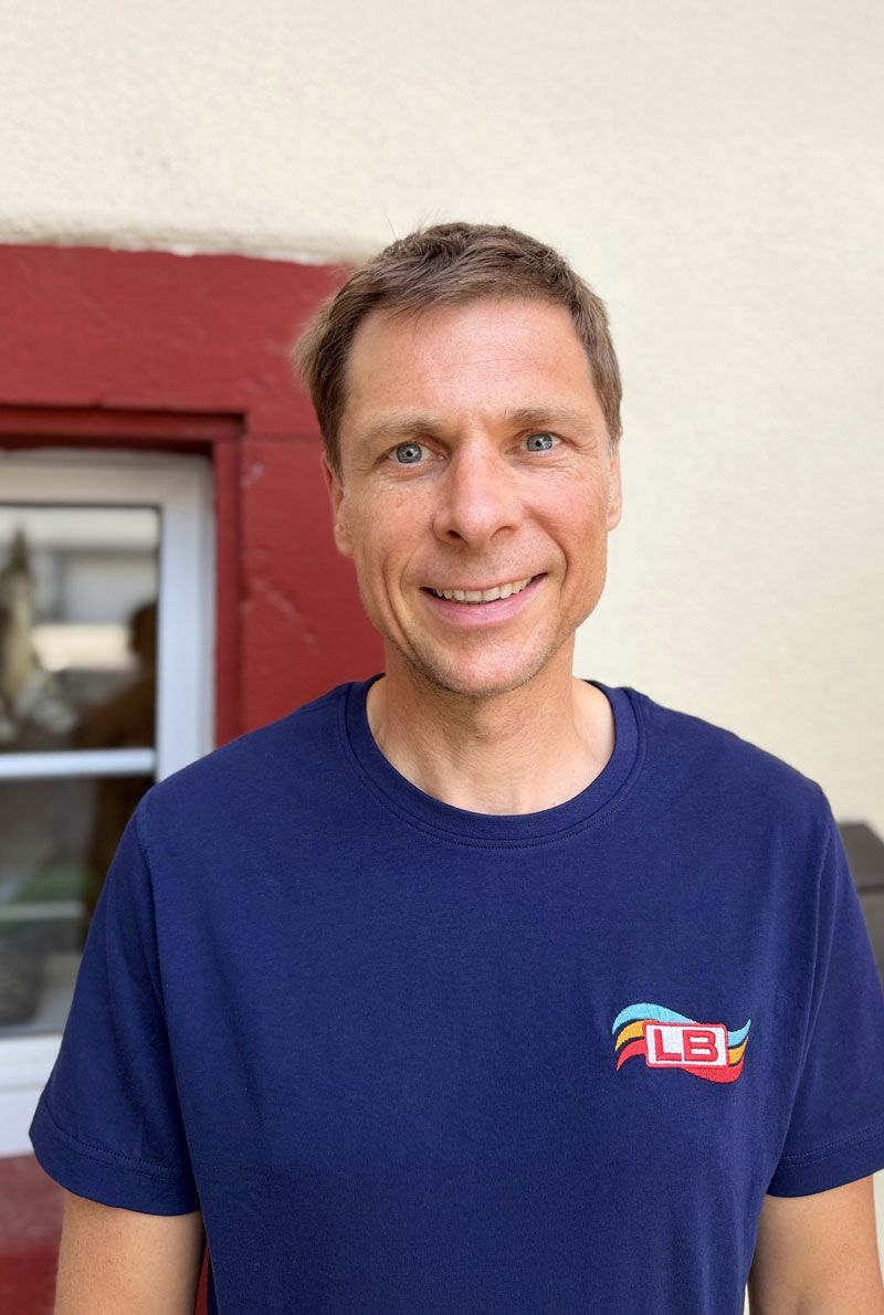 Ein junger Mann mit Brille und blauem Hemd lächelt