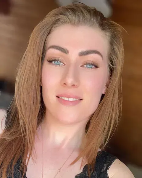 Eine Frau mit langen Haaren und blauen Augen lächelt in die Kamera.