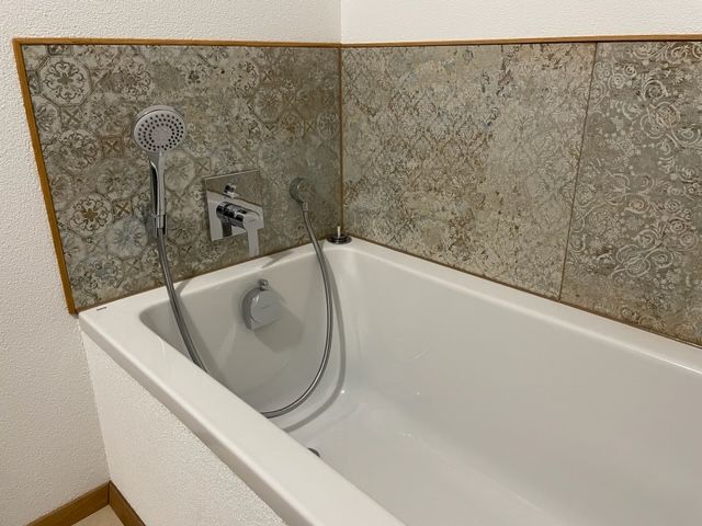 Eine Badewanne mit angeschlossenem Duschkopf in einem Badezimmer.