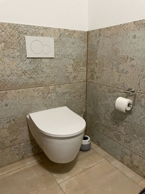 Ein Badezimmer mit Toilette und Papierhandtuchhalter