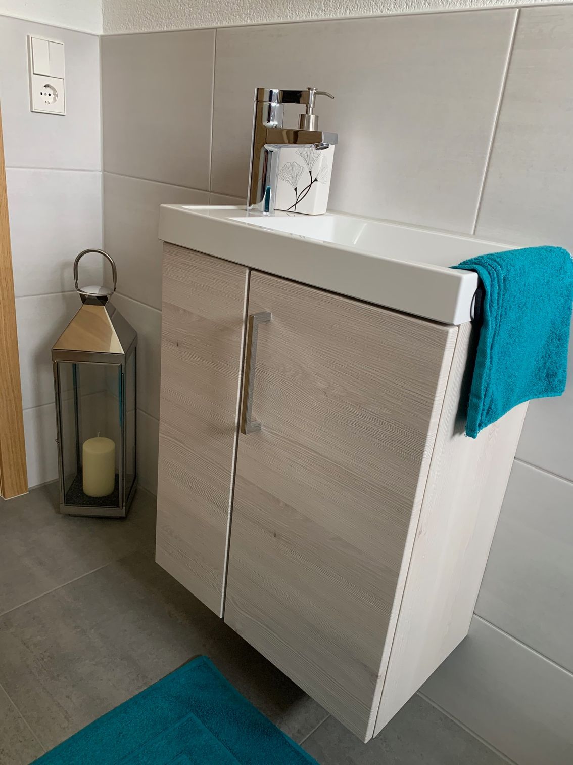 Ein Badezimmer mit Waschbecken, Laterne und Handtuch