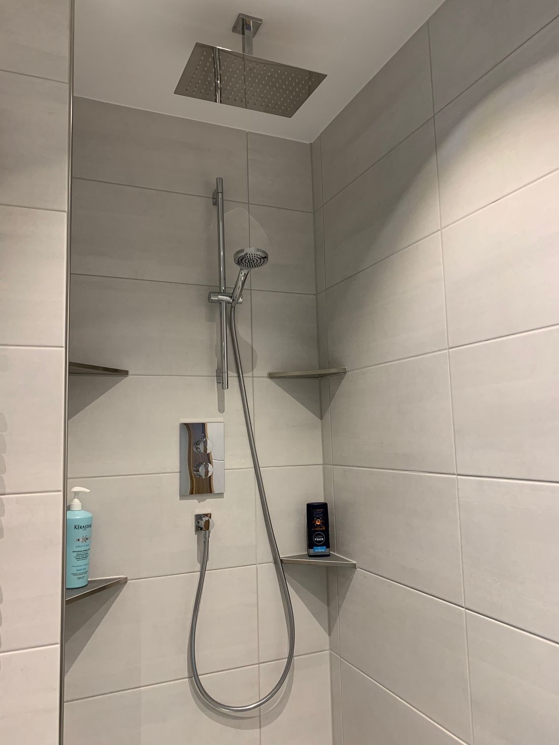 In einem Badezimmer hängt ein Duschkopf von der Decke.