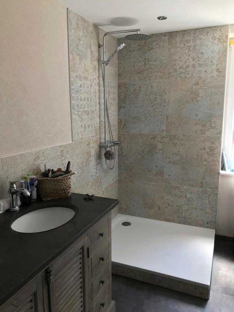 Ein Badezimmer mit Waschbecken und ebenerdiger Dusche.