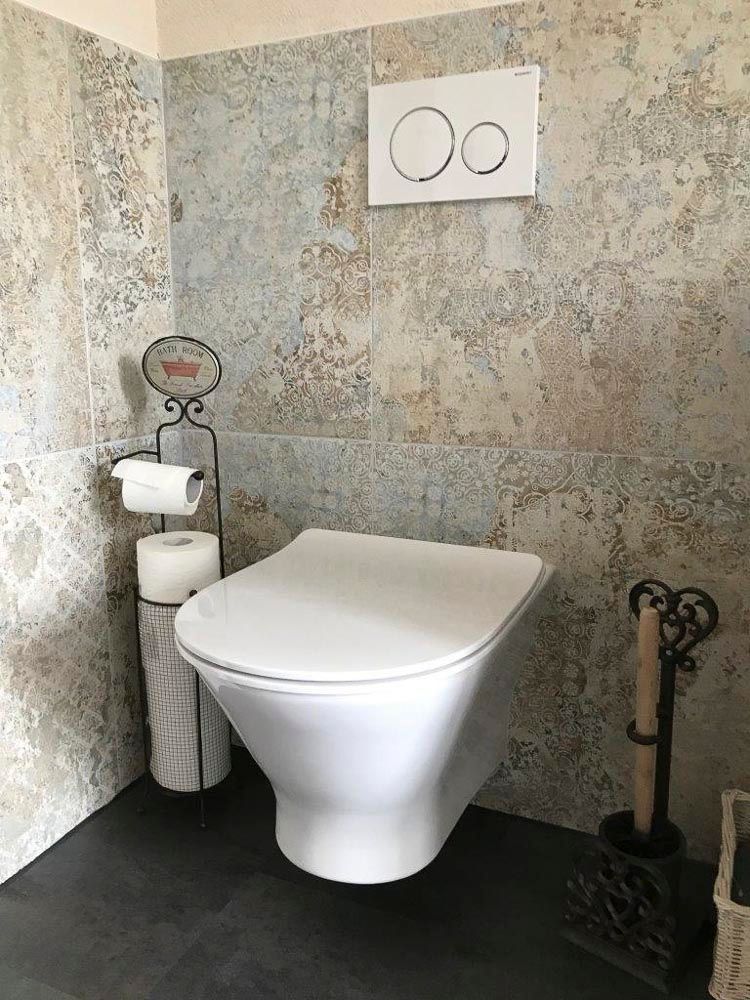 Eine weiße Toilette steht in einem Badezimmer neben einem Papierhandtuchhalter.