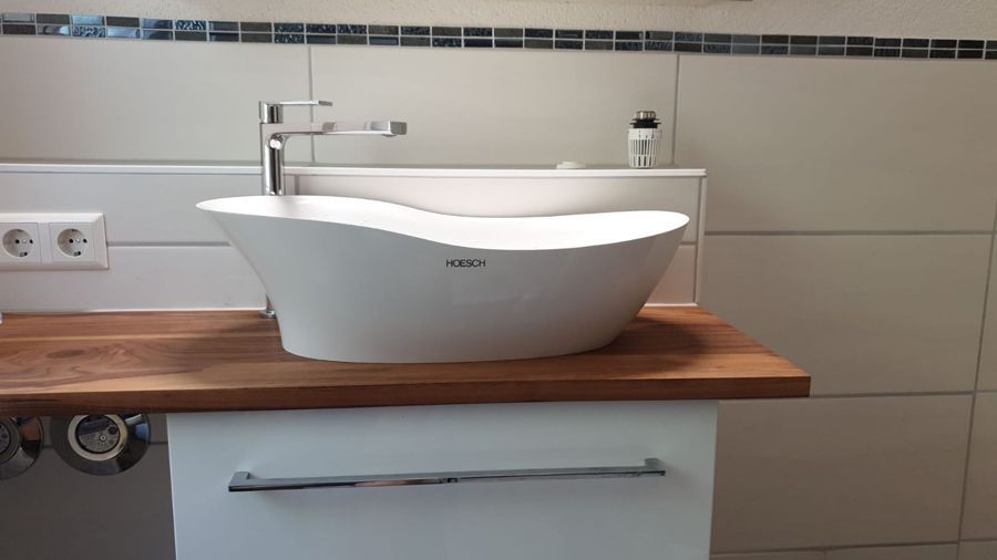 Ein Waschbecken im Badezimmer steht auf einer hölzernen Arbeitsplatte