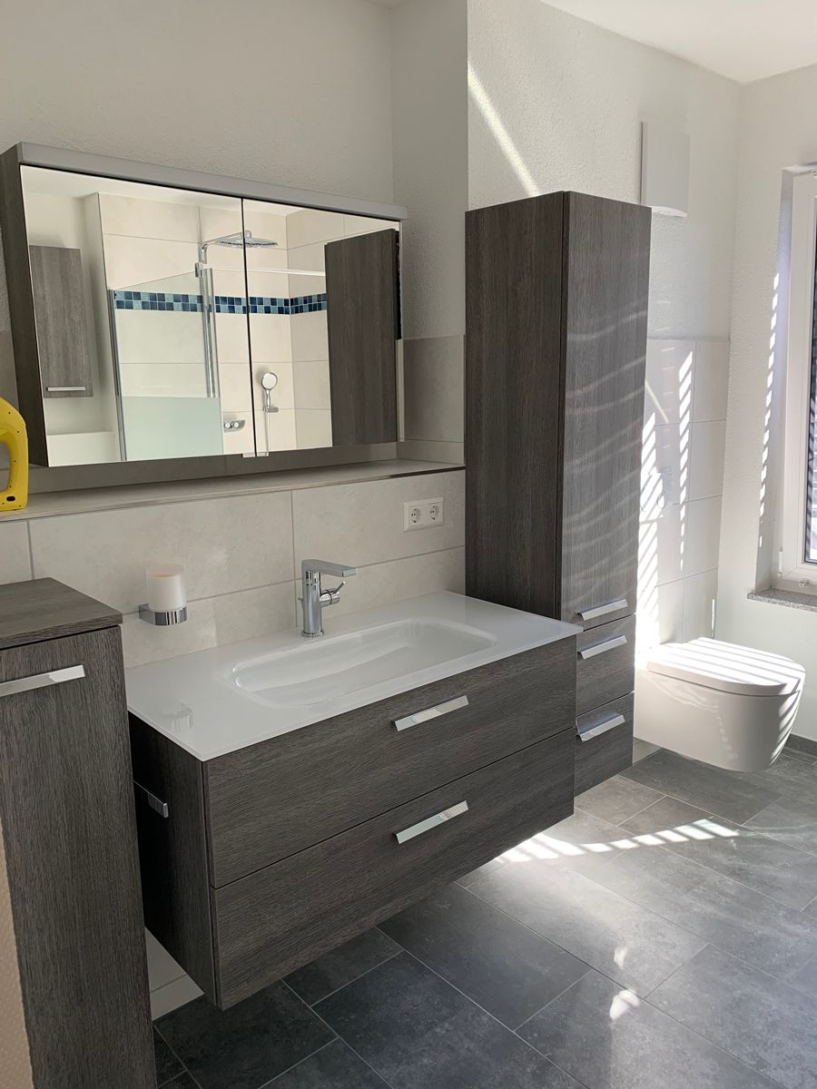 Ein Badezimmer mit Waschbecken, Toilette, Spiegel und Schränken.