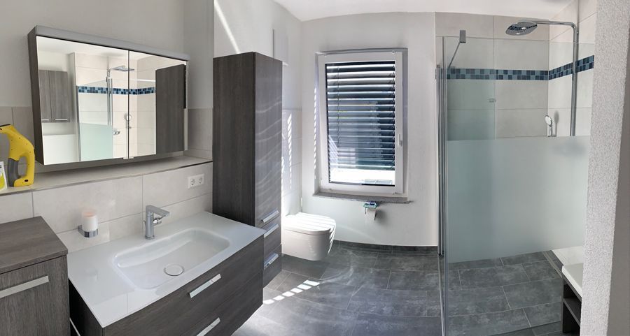 Ein Badezimmer mit Waschbecken, Spiegel und ebenerdiger Dusche.