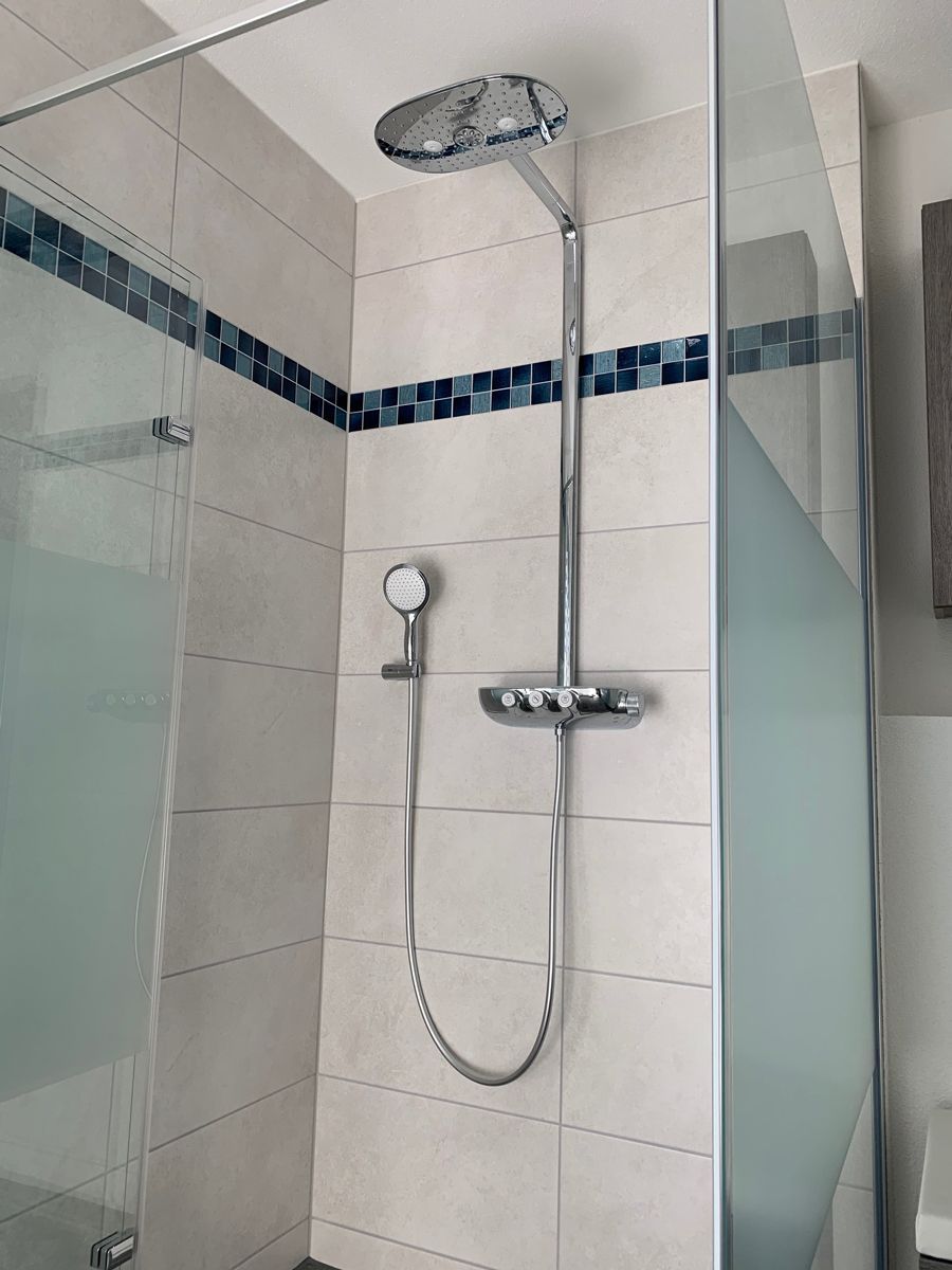 Ein Badezimmer mit Duschkopf und Glastür