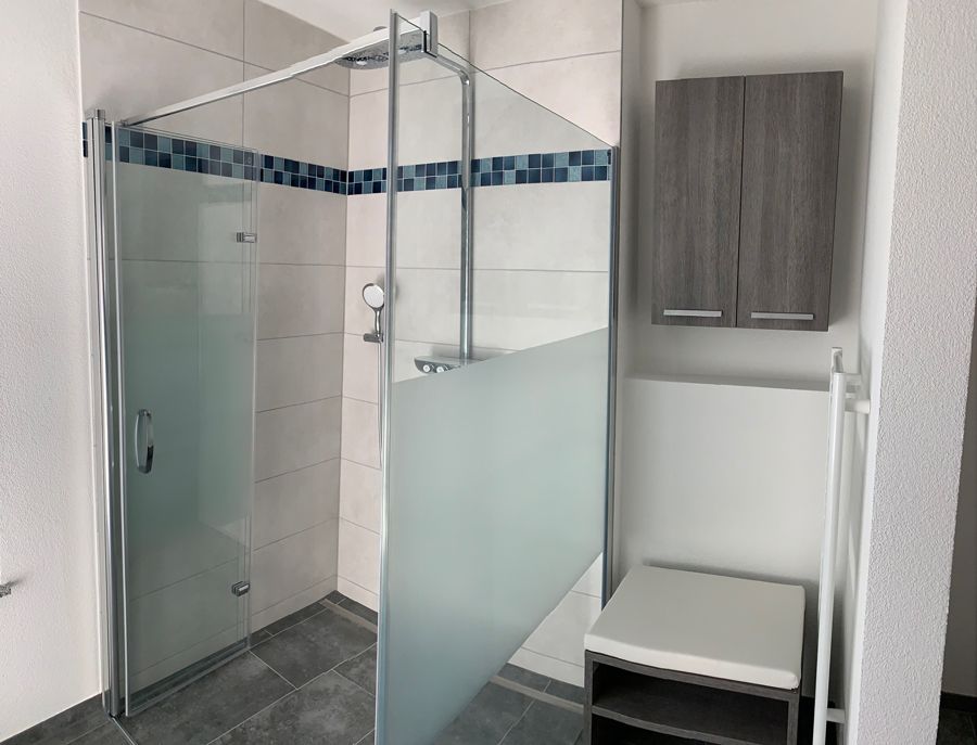 Ein Badezimmer mit ebenerdiger Dusche und Schrank