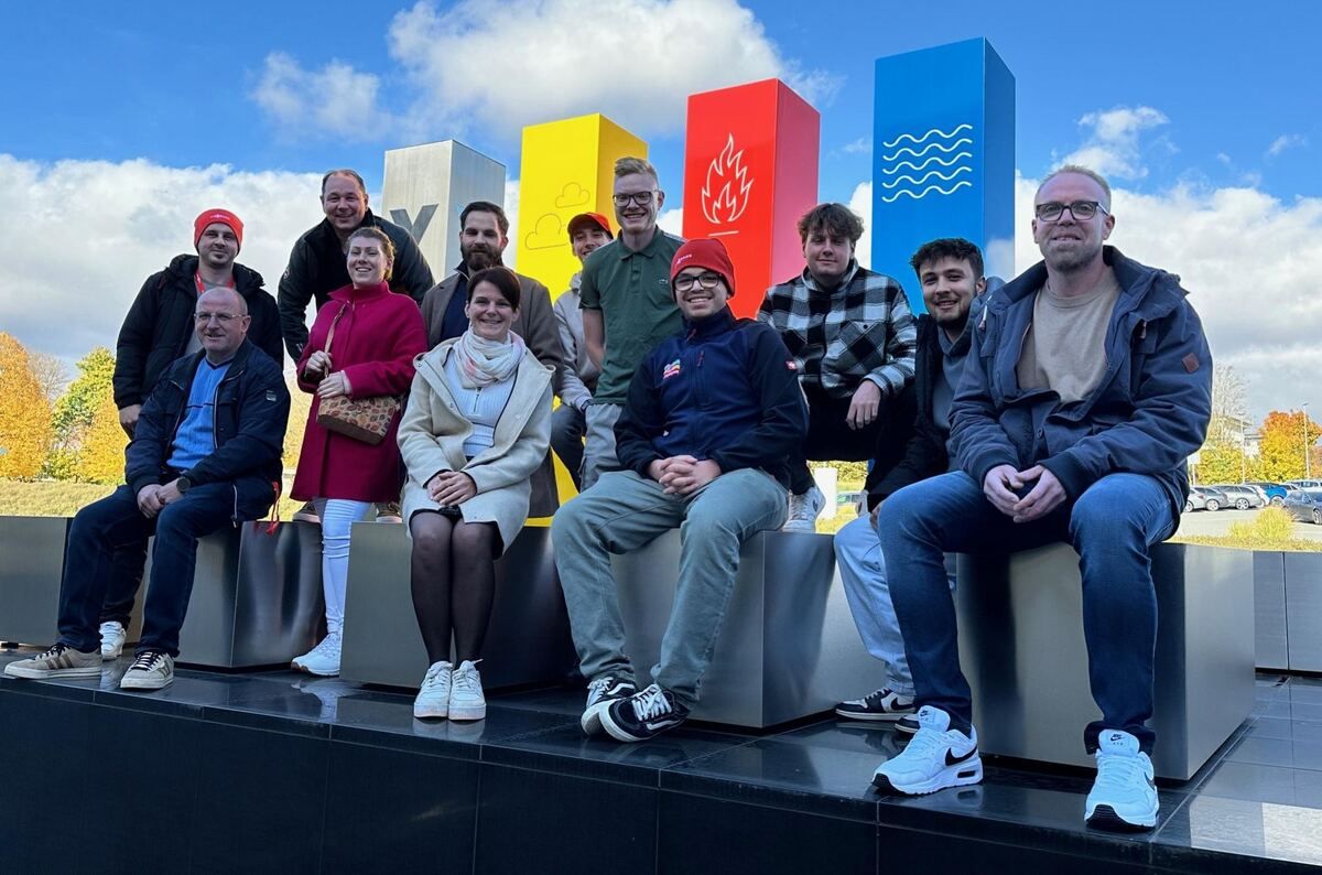 Eine Gruppe von Menschen posiert auf einer Bank sitzend für ein Foto.