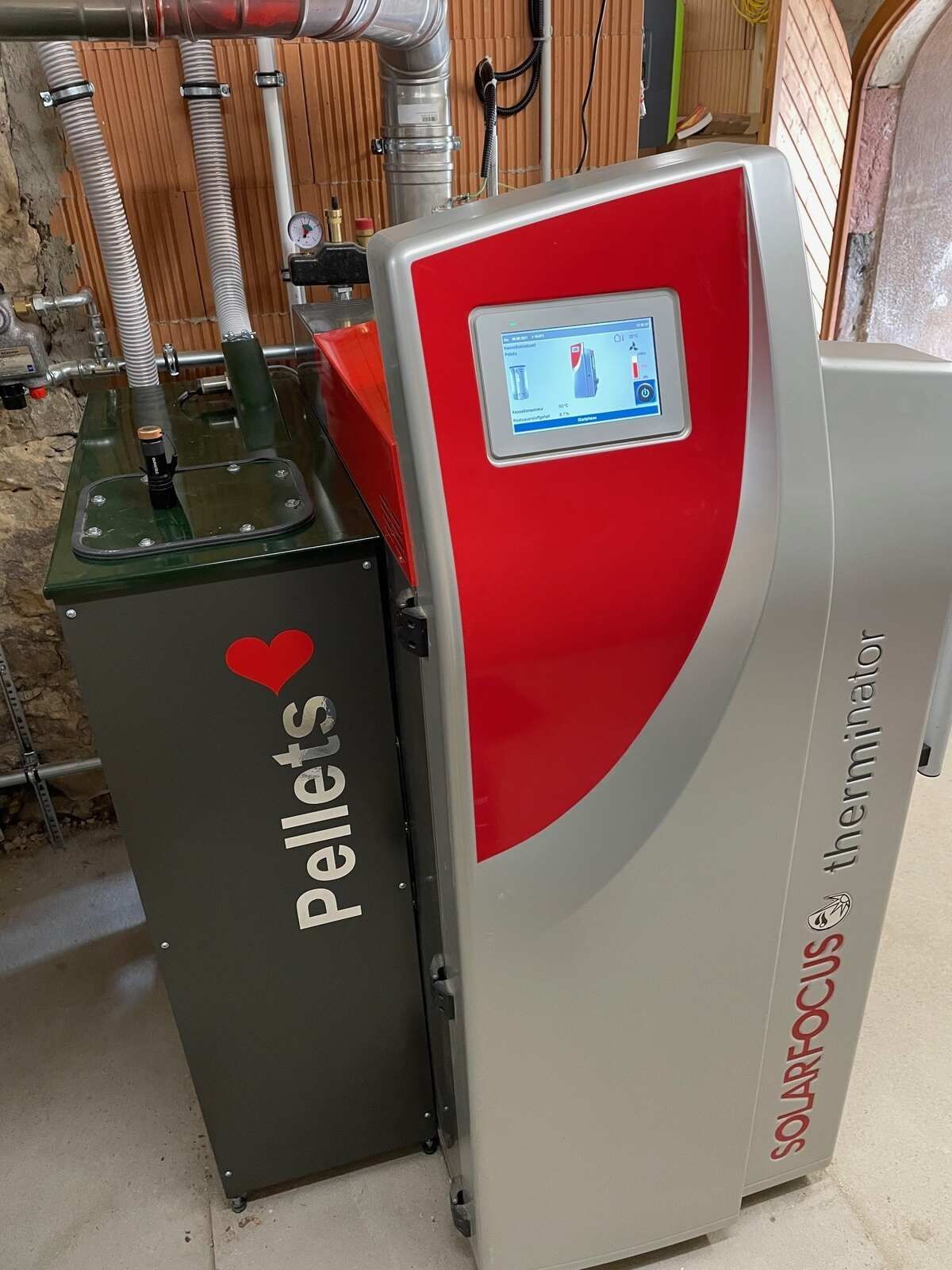 Eine Maschine mit einem Bildschirm steht neben einer Schachtel mit der Aufschrift „Pellets“.