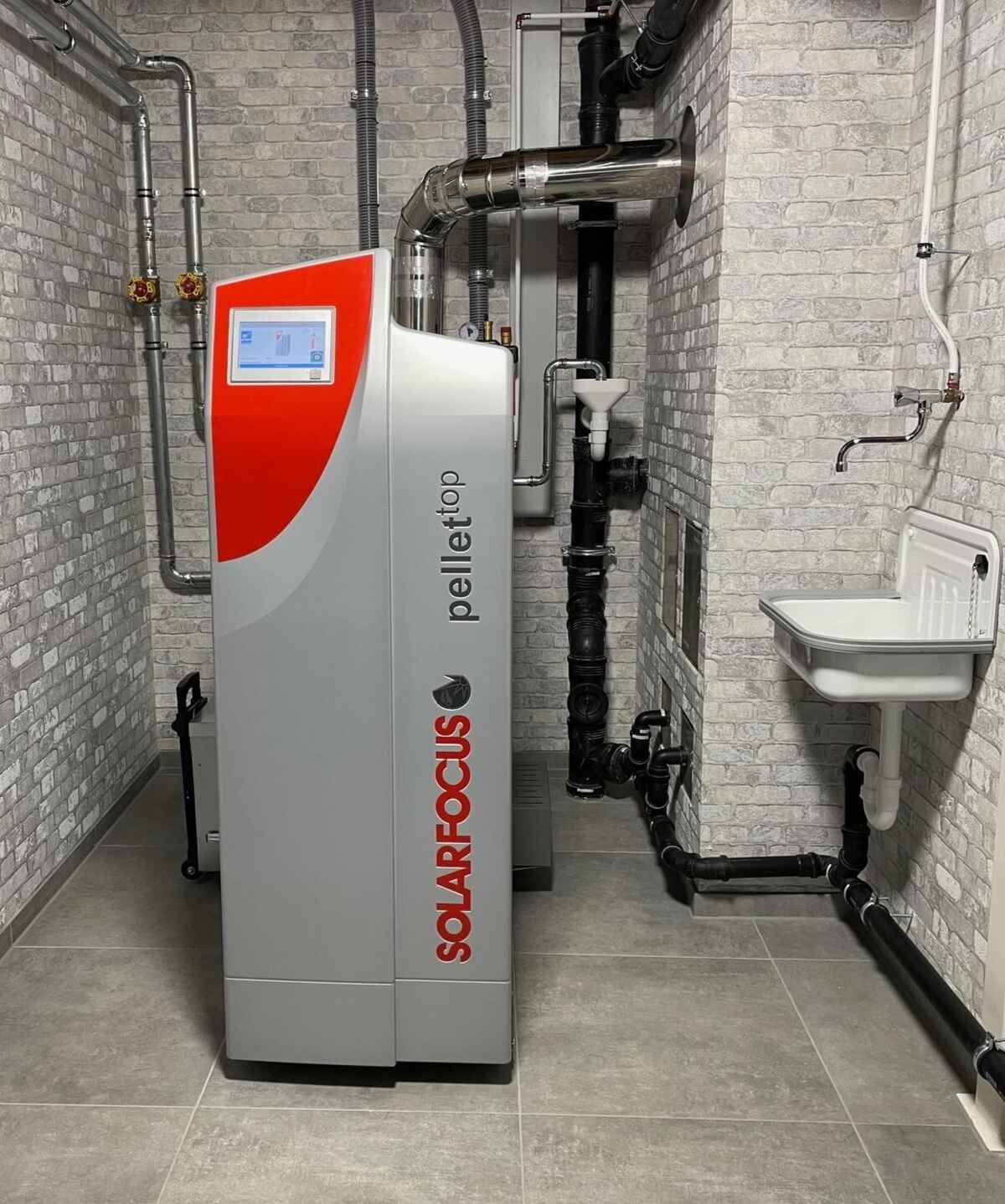 Ein Solarfocus Pelletkessel steht in einem Raum neben einem Waschbecken