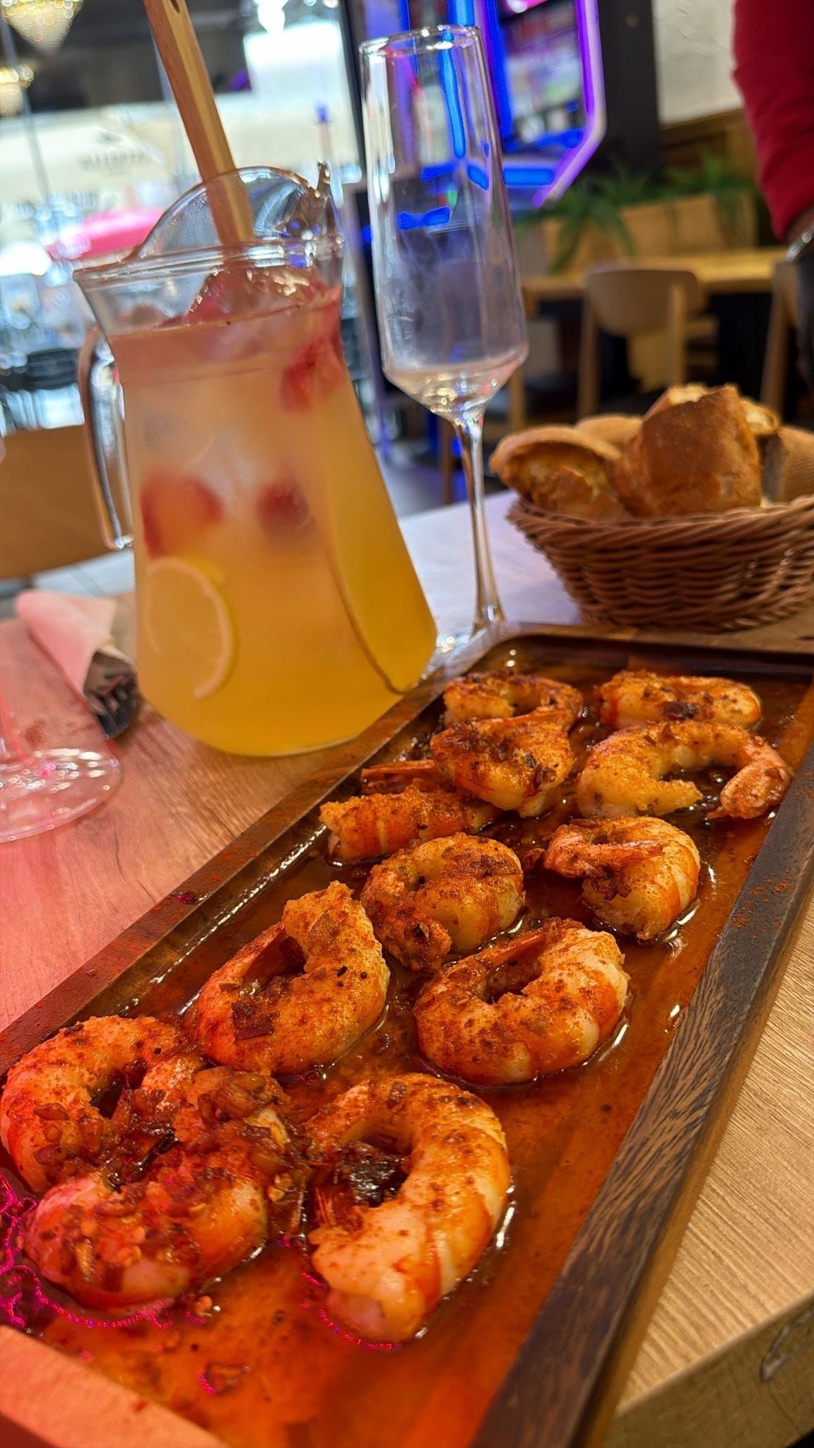 Plato de camarones con bebidas, incluida una jarra de limonada, en una mesa de restaurante.