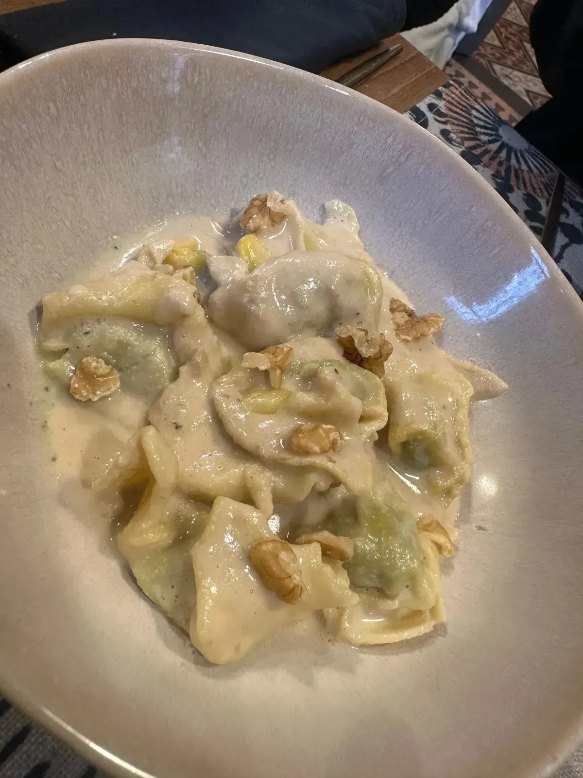 Pasta en salsa cremosa con nueces, servida en un recipiente ovalado blanco.